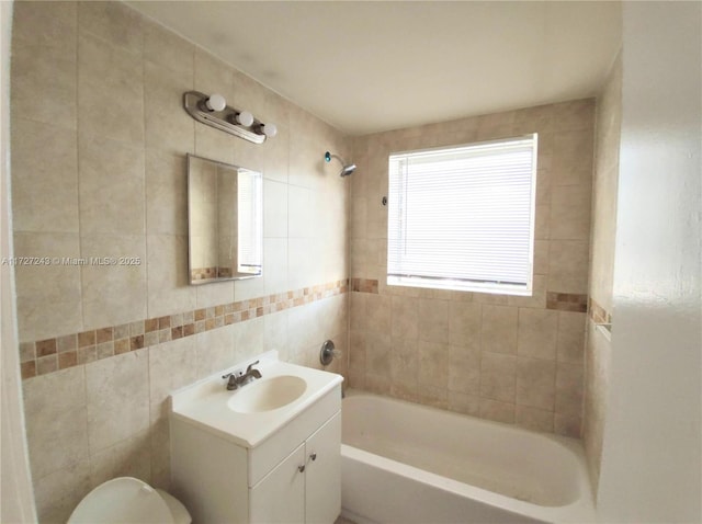 full bathroom with toilet, vanity, tile walls, and tiled shower / bath combo