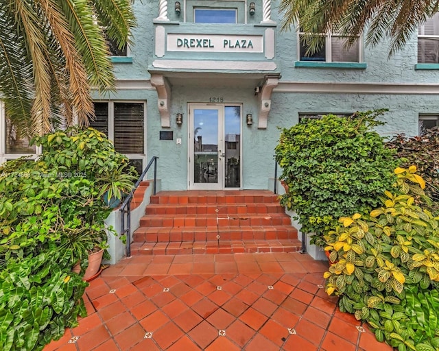 view of exterior entry featuring french doors and stucco siding