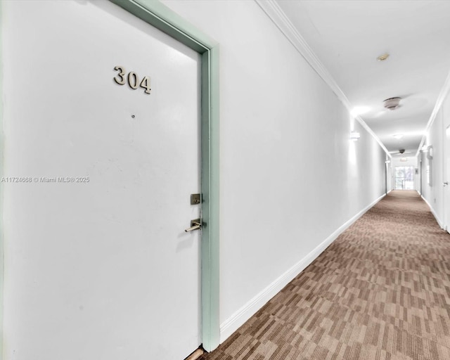 hallway with carpet floors, ornamental molding, and baseboards