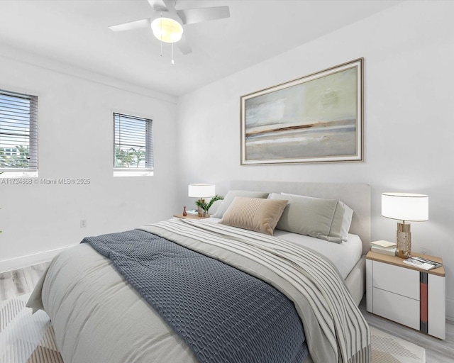 bedroom with ceiling fan, baseboards, and light wood finished floors