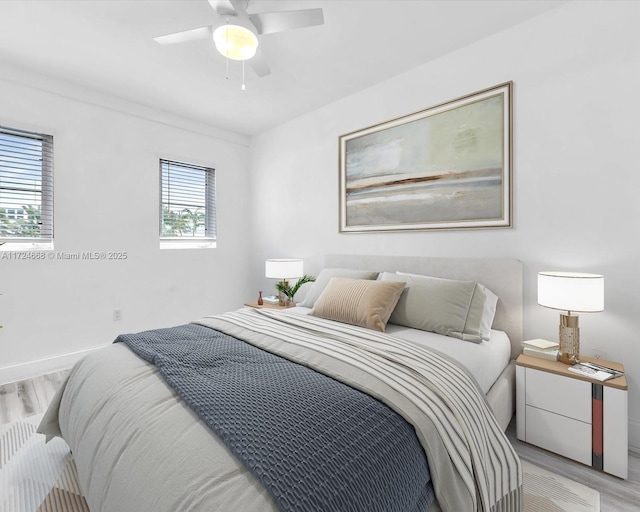 bedroom featuring ceiling fan, ornamental molding, light hardwood / wood-style floors, and multiple windows