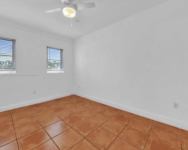 empty room with baseboards, a ceiling fan, and light tile patterned floors