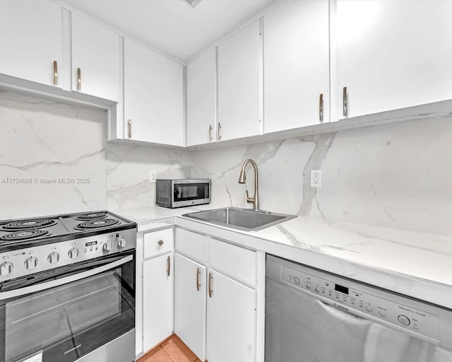 kitchen with appliances with stainless steel finishes, backsplash, white cabinets, and sink