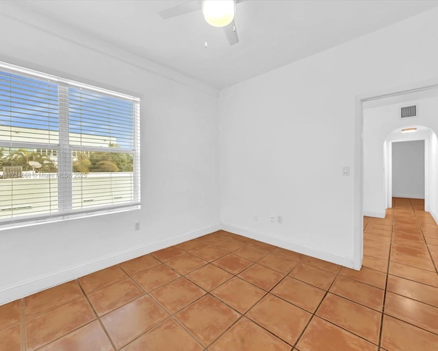 empty room featuring ceiling fan, arched walkways, visible vents, and light tile patterned floors