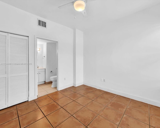 unfurnished bedroom with ceiling fan, light tile patterned floors, a closet, and connected bathroom