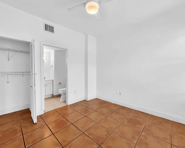 unfurnished bedroom featuring ceiling fan, a closet, tile patterned floors, and ensuite bathroom