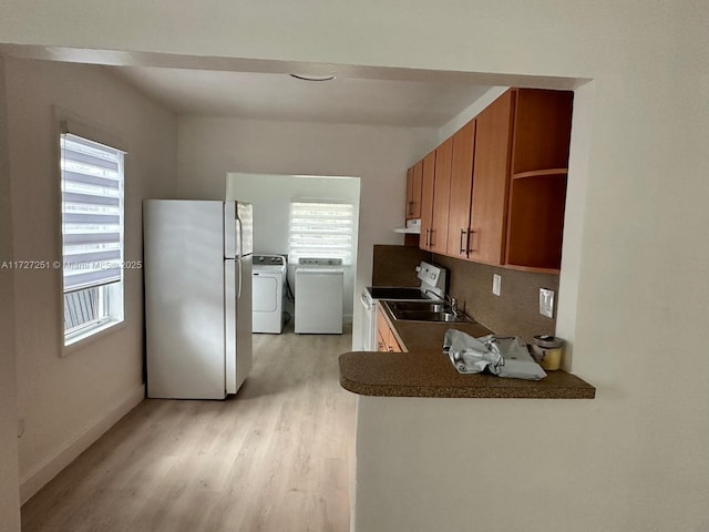 kitchen with sink, white appliances, independent washer and dryer, extractor fan, and light hardwood / wood-style floors