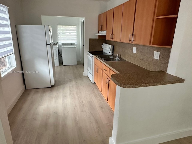 kitchen featuring sink, white appliances, washer and clothes dryer, backsplash, and light hardwood / wood-style floors