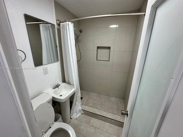 bathroom with sink, curtained shower, tile patterned floors, and toilet