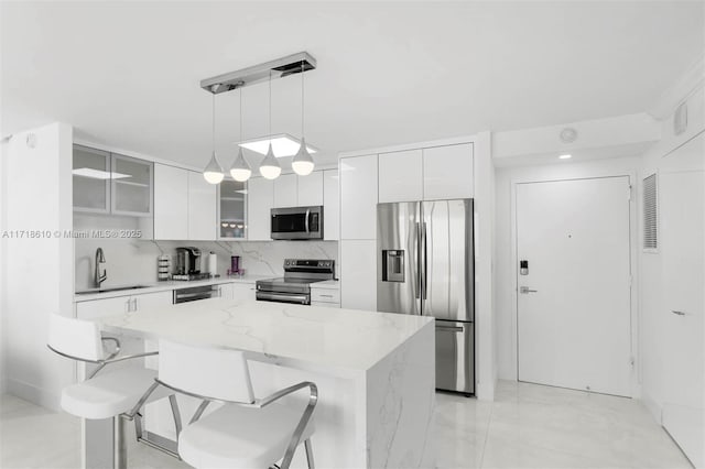 kitchen featuring hanging light fixtures, white cabinets, appliances with stainless steel finishes, and tasteful backsplash