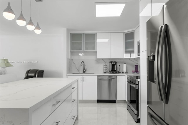 kitchen with decorative light fixtures, sink, stainless steel appliances, and white cabinetry