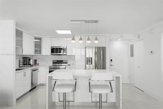 kitchen with a kitchen island, pendant lighting, appliances with stainless steel finishes, a breakfast bar area, and white cabinets