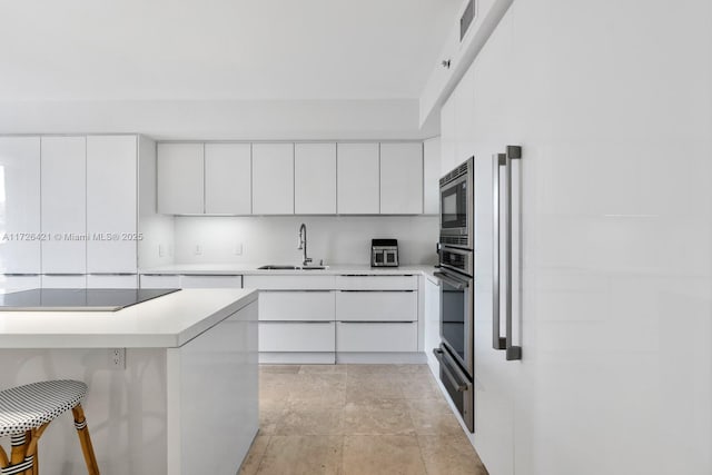 kitchen featuring white cabinets, a kitchen bar, sink, and stainless steel appliances