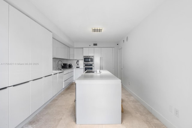 kitchen featuring white cabinetry, sink, stainless steel appliances, and a center island