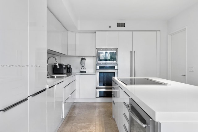 kitchen featuring white cabinetry, stainless steel appliances, a kitchen island, and sink