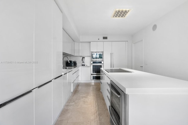 kitchen with a center island, decorative backsplash, sink, stainless steel appliances, and white cabinets