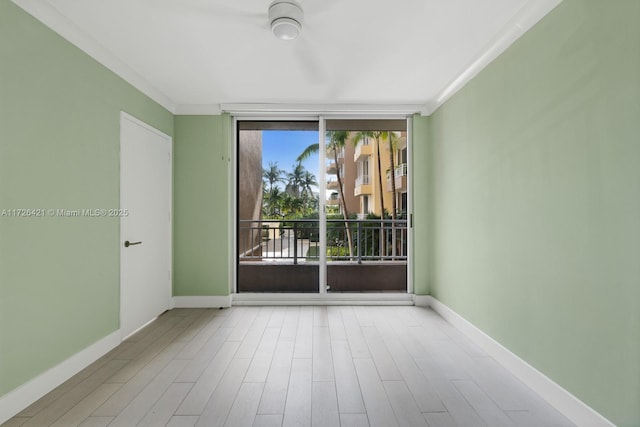 empty room featuring light wood-type flooring, crown molding, plenty of natural light, and expansive windows