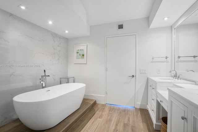 bathroom featuring hardwood / wood-style floors, vanity, a bathing tub, and tile walls