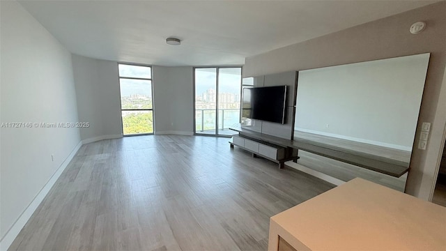 unfurnished living room with floor to ceiling windows and light hardwood / wood-style flooring