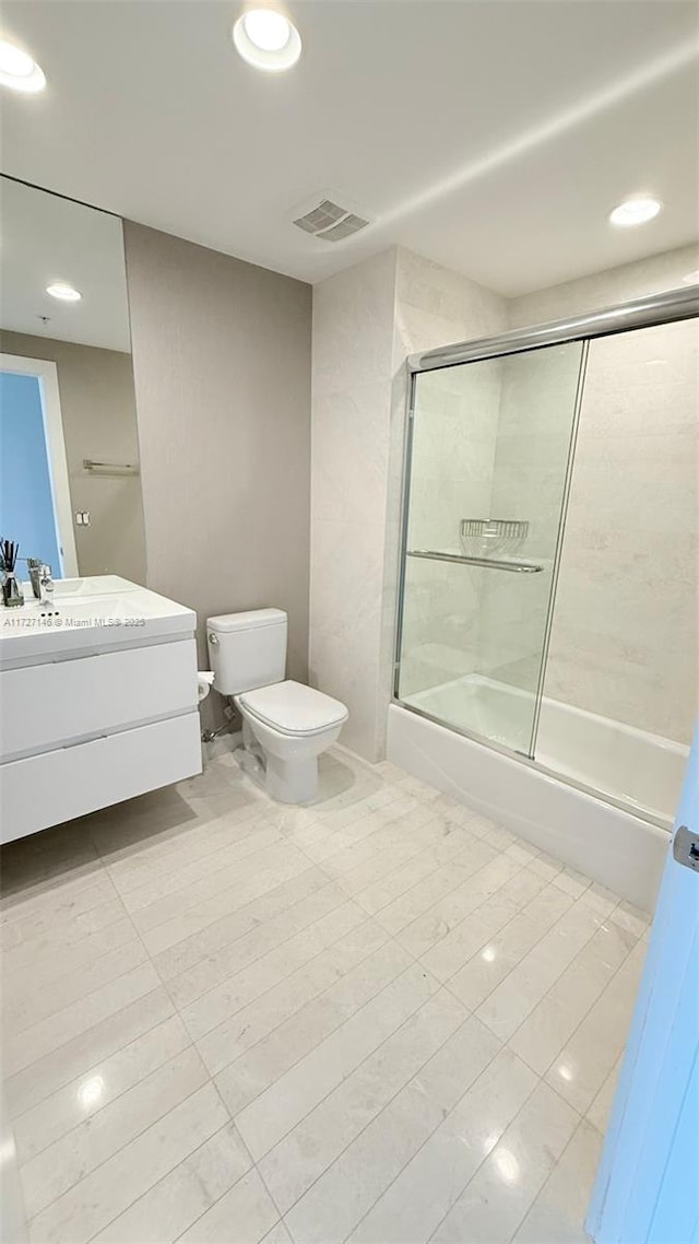 full bathroom with bath / shower combo with glass door, toilet, vanity, and tile patterned flooring