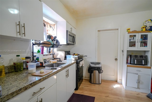 kitchen with white cabinetry, sink, black electric range, light wood-type flooring, and stone counters