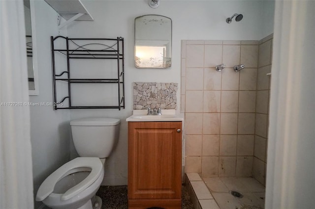 bathroom with toilet, vanity, and tiled shower