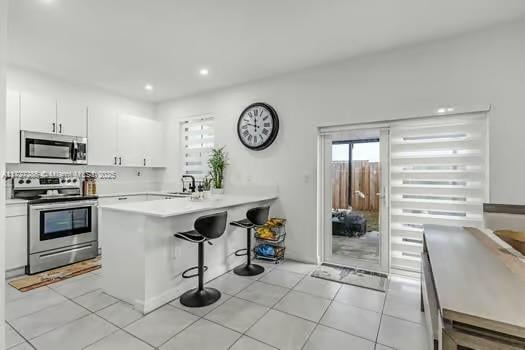 kitchen featuring a breakfast bar area, white cabinets, kitchen peninsula, and stainless steel appliances