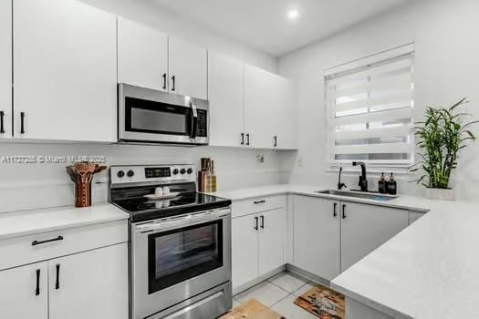 kitchen featuring light tile patterned flooring, stainless steel appliances, white cabinetry, and sink