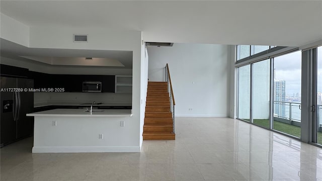 kitchen featuring black fridge with ice dispenser, light tile patterned flooring, floor to ceiling windows, and sink