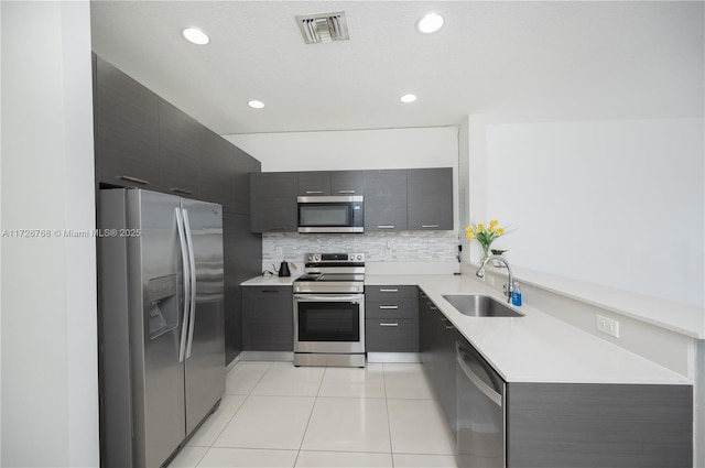 kitchen with light tile patterned floors, backsplash, sink, and stainless steel appliances