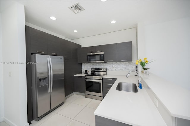 kitchen with light tile patterned floors, sink, backsplash, and appliances with stainless steel finishes