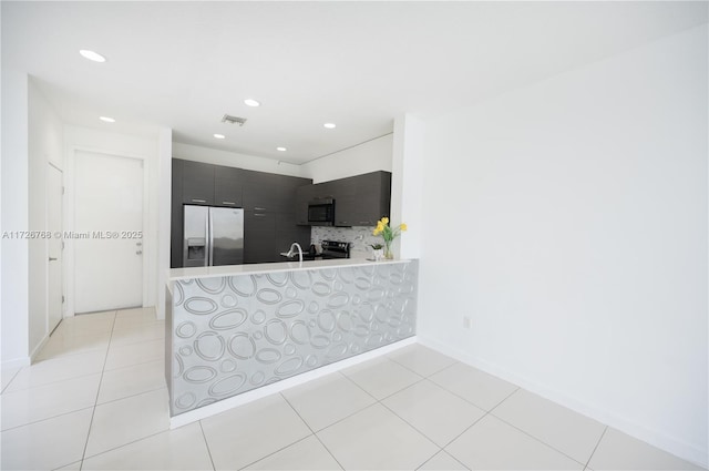 kitchen featuring light tile patterned flooring, stainless steel appliances, decorative backsplash, and kitchen peninsula