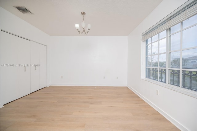 interior space with a textured ceiling, light hardwood / wood-style floors, and a notable chandelier