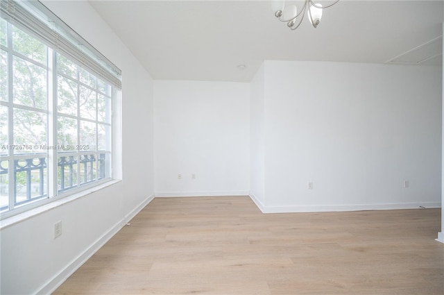 empty room featuring a chandelier and light hardwood / wood-style floors