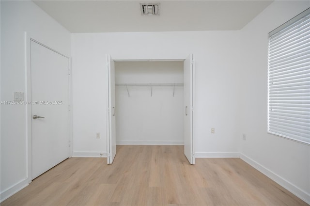 unfurnished bedroom with light wood-type flooring and a closet