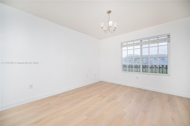 empty room featuring light hardwood / wood-style floors and an inviting chandelier