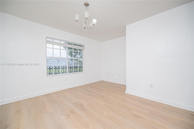 spare room with light hardwood / wood-style flooring and a notable chandelier