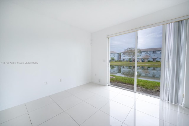 unfurnished room with light tile patterned floors and a water view