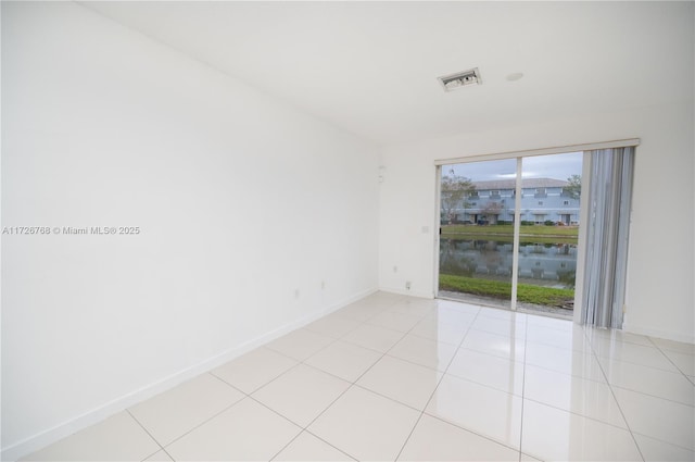 spare room with a water view and light tile patterned floors