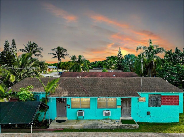 view of front of property featuring a wall mounted AC and solar panels