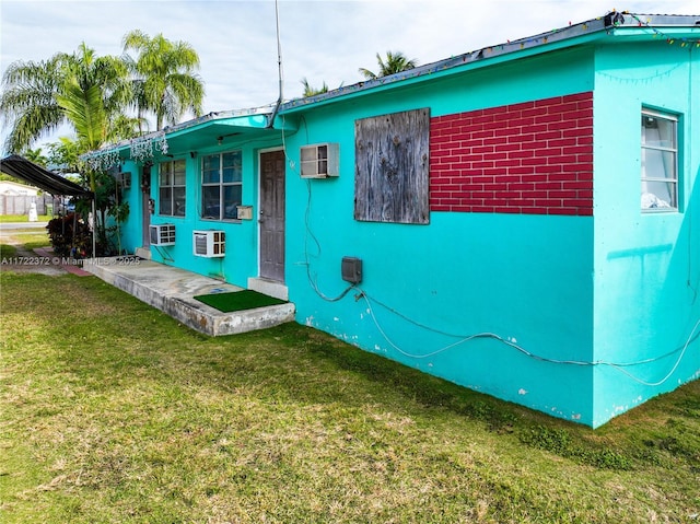 exterior space with a lawn and a wall mounted air conditioner