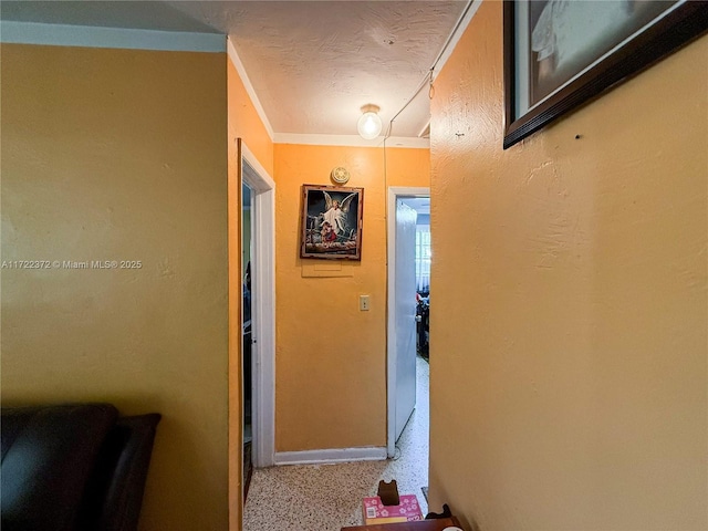 hall with a textured ceiling and ornamental molding