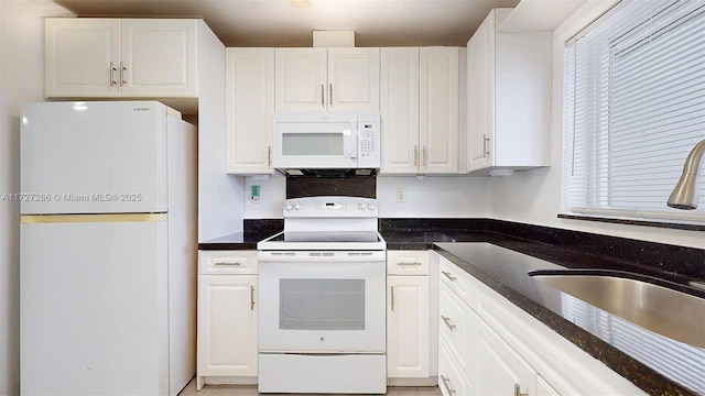 kitchen featuring sink, white appliances, white cabinets, and dark stone countertops