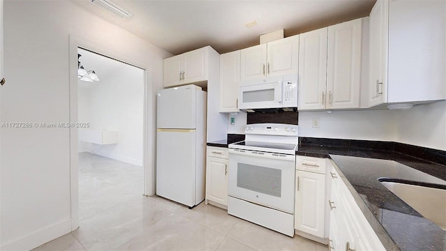 kitchen featuring dark stone countertops, sink, white appliances, hanging light fixtures, and white cabinets