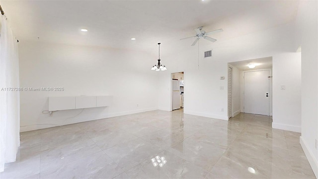 unfurnished room featuring ceiling fan with notable chandelier and a towering ceiling