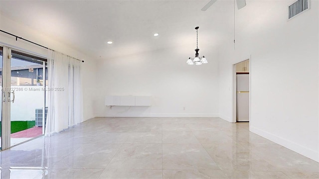 spare room featuring ceiling fan with notable chandelier