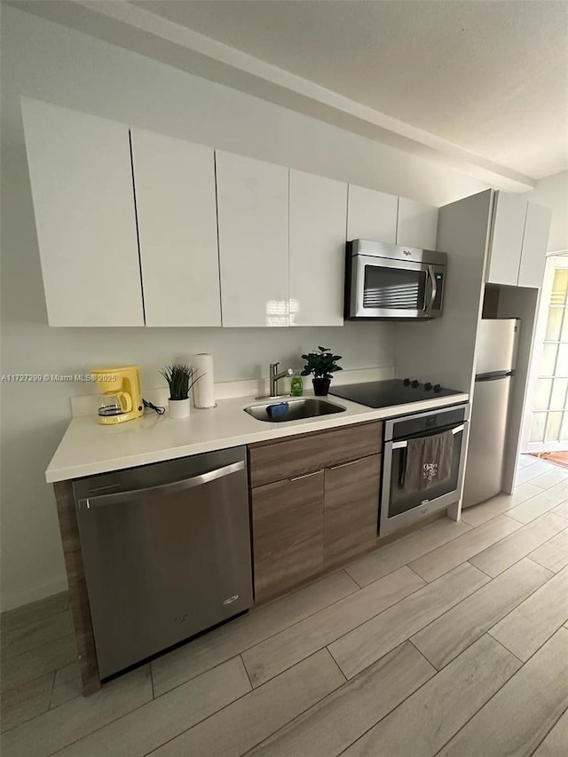 kitchen with appliances with stainless steel finishes, sink, and white cabinetry