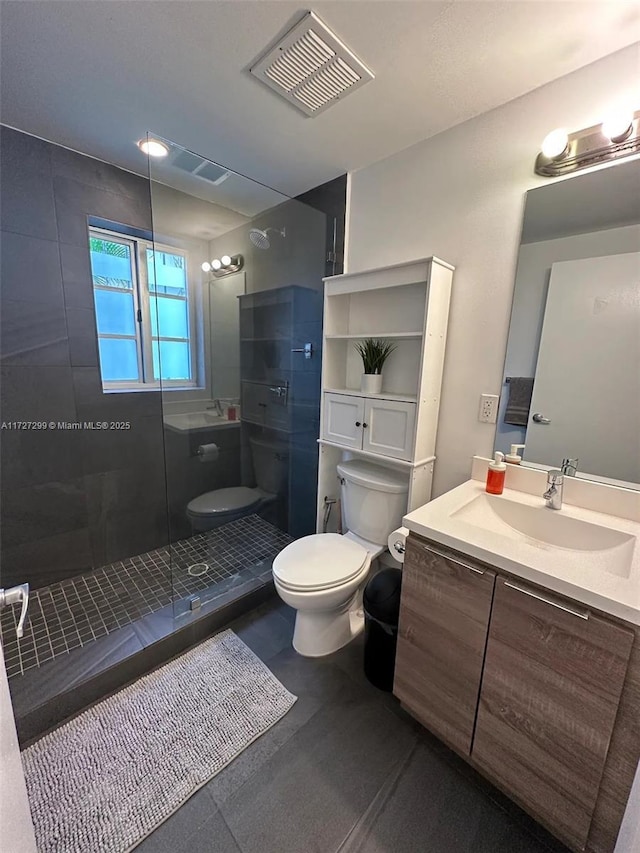 bathroom with tiled shower, vanity, and toilet