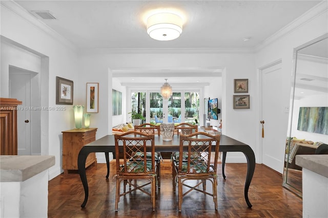 dining area with dark parquet flooring, ornamental molding, and french doors