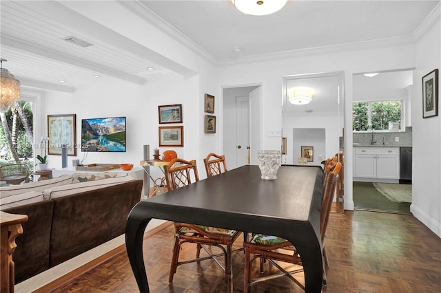 dining area featuring sink, dark parquet flooring, ornamental molding, and beam ceiling